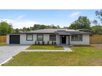 Charming, single-story home featuring a well-manicured lawn, solar panels and a freshly paved driveway at 51 Spruce Ln, Debary, FL 32713