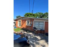 Orange one story home showing windows and electrical components with a partial view of a black car at 1231 Leon Ln, Daytona Beach, FL 32117