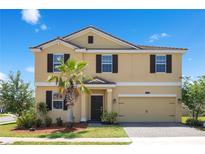 Two-story home with a two-car garage, a palm tree, and neutral-colored exterior with brown shutters at 1504 Oak Marsh Loop, Davenport, FL 33837