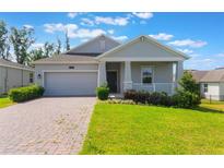 Charming one-story home featuring a well-manicured lawn and inviting covered front porch at 1757 Brush Cherry Pl, Ocoee, FL 34761