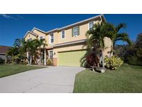 Two-story home with a light yellow exterior, a green two car garage door, and tropical landscaping at 207 Black Springs Ln, Winter Garden, FL 34787