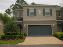 Exterior of home with a two car garage, tan siding, and a paver driveway at 411 Evening Sky Dr, Oviedo, FL 32765