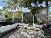 Condominium building with a gray exterior, staircase, and lush trees providing shade at 4328 Aqua Vista Dr # B, Orlando, FL 32839