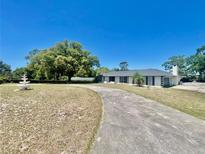 Charming one-story home featuring a classic architectural design, mature trees, and a spacious circular driveway at 6001 Beau Ln, Orlando, FL 32808