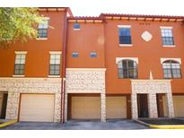 Three-story townhome with tan exterior paint, white garage doors, and multi-pane windows at 6117 Metrowest Blvd # 106, Orlando, FL 32835