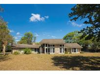 Two-story home with stone accents, large windows, and mature landscaping on a sunny day at 8735 Rancho Ct, Orlando, FL 32836