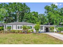 Charming gray home with manicured landscaping and a convenient carport, showcasing curb appeal at 1145 Utah Blvd, Orlando, FL 32803