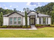 Charming single-story home with stone accents, manicured landscaping, and a modern glass front door at 16500 Magnolia Terrace Blvd, Montverde, FL 34756