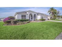 Beautiful single-story home with manicured lawn, arched entry, and lush landscaping with ample curb appeal at 409 Belfry Dr, Davenport, FL 33897