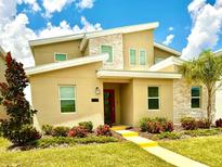 Beautiful two-story home boasts a modern design, stone accents, and colorful landscaping at 9312 Sommerset Hills Dr, Davenport, FL 33896
