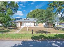 Charming single-story home with a brick facade, well-maintained lawn, and mature trees under a blue sky at 1030 Gran Paseo Dr, Orlando, FL 32825