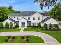 Stunning two-story white home showcasing manicured landscaping, stone accents, and a circular driveway at 1761 Legion Dr, Winter Park, FL 32789