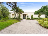 Stunning modern home with a sprawling driveway, lush landscaping, and palm trees at 608 E Club Cir, Longwood, FL 32779