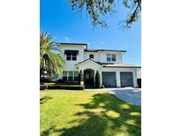 Charming two-story home with a well-manicured lawn, palm trees, and a three car garage at 1690 Palm Ave, Winter Park, FL 32789