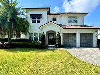 Beautifully landscaped two-story home featuring a manicured lawn and a two-car garage at 1690 Palm Ave, Winter Park, FL 32789
