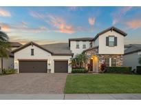 Beautiful two-story home showcasing stone accents, a well-manicured lawn, and a three-car garage at 8017 Chilton Dr, Orlando, FL 32836