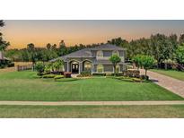 Stunning two-story home featuring arched windows and a lush, landscaped front yard at 13710 Lake Cawood Dr, Windermere, FL 34786