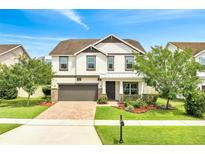 Charming two-story home with manicured lawn, lush landscaping, brick driveway, and a two car garage at 14883 Golden Sunburst Ave, Orlando, FL 32827
