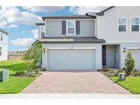 Charming townhome featuring a two-car garage, brick driveway, and well-manicured landscaping at 16430 Bird Of Paradise Ave, Clermont, FL 34714