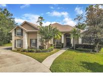 Charming stucco two-story home with a well-manicured lawn and mature landscaping under a bright blue sky at 8740 Ingleton Ct, Orlando, FL 32836