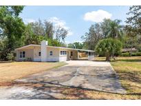 Single story home featuring a chimney, large driveway, and a covered side patio at 2637 Florence St, Orlando, FL 32818
