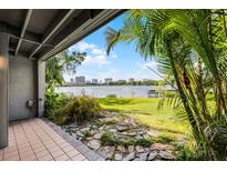Covered back patio with stone and tile flooring leads to a lush yard and scenic lake views at 370 Lakeview St, Orlando, FL 32804