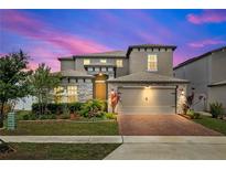 Beautiful two-story home featuring a brick driveway, attached two-car garage, and manicured landscaping at 5637 Beggs Road, St Cloud, FL 34771