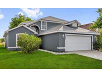 Charming gray two-story home with a well-manicured lawn and a two-car garage at 1851 Wimbledon St, Kissimmee, FL 34743
