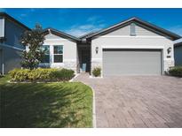 Charming single-story home with a manicured lawn, brick driveway, and two-car garage at 2168 Marsh Sedge Ln, Winter Park, FL 32792