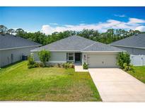 Well-maintained single-story home featuring a lush green lawn and a two car garage at 284 Talladega Ln, Polk City, FL 33868
