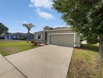 Charming single-story home with a well-maintained lawn, a palm tree, and a two-car garage at 4841 Hickory Stream Ln, Mulberry, FL 33860