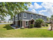 A two-story townhome has a patio with seating overlooking a large lawn and a serene lake at 6672 S Goldenrod Rd # 132B, Orlando, FL 32822