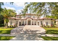 Elegant two-story home features a red tile roof, large brick driveway, and manicured landscaping at 11019 Kentmere Ct, Windermere, FL 34786