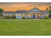 Charming home with shuttered windows, front porch with wooden columns and a large lawn at sunset at 1271 Thoroughbred Trl, Sanford, FL 32771
