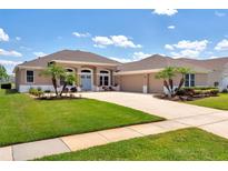 Beautifully landscaped single-story home with a well-manicured lawn, blue front door, and a two-car garage at 13111 Meergate Cir, Orlando, FL 32837