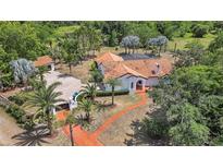 Aerial view of a Spanish-style home with a terracotta roof, lush landscaping, and a circular driveway at 13124 Filly Ct, Windermere, FL 34786