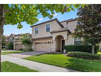 Charming two-story home showcasing a manicured lawn and a convenient two-car garage with a brick paved driveway at 1425 Thunderbird Rd, Davenport, FL 33896