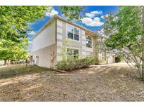 Two-story home with a mix of stucco and siding and trimmed windows, nestled amongst mature trees and a green front lawn at 2995 White Magnolia Loop, Clermont, FL 34711