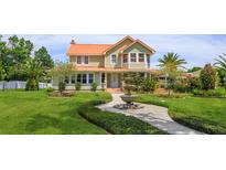 Charming two-story home with lush landscaping, mature trees, and a decorative fountain in the front yard at 36408 E Eldorado Lake Dr, Eustis, FL 32736