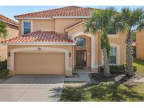 Charming two-story home featuring a red tile roof, arched doorway, and well-maintained landscaping with mature palm trees at 411 Cabello Dr, Davenport, FL 33837