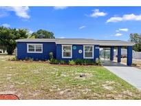 Charming blue house with well-maintained front yard and covered parking area at 507 Raymond Ave, Frostproof, FL 33843