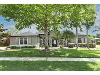 Charming single-story home featuring a beautifully landscaped front yard with a large tree for shade at 753 Grey Heron Pl, Chuluota, FL 32766