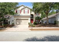 Charming two-story home with red shutters, a well-manicured lawn and a brick driveway at 143 Windsor Pl, Davenport, FL 33896