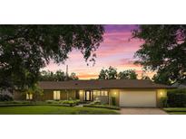 Charming ranch-style home with well-manicured lawn and mature trees in a tranquil setting at dusk at 1618 Pepperidge Dr, Orlando, FL 32806