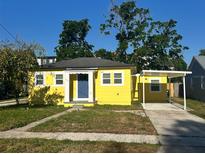 Charming yellow home with a blue front door and covered carport offers curb appeal at 5216 Davisson Ave, Orlando, FL 32810