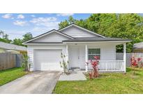Charming single-story home with an attached garage, front porch, and landscaping at 6148 Landrace Ln, Orlando, FL 32807