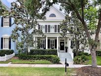 Charming two-story home featuring black shutters, elegant columns, and a well-manicured front yard at 616 Nadina Pl, Celebration, FL 34747