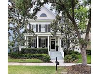 Charming two-story home featuring a welcoming porch, black shutters, and well-manicured landscaping at 616 Nadina Pl, Celebration, FL 34747