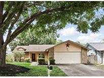 Charming single-story home with a well-manicured lawn, mature trees, and a two-car garage at 10049 Custer Cir, Orlando, FL 32817