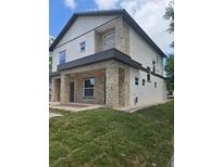 Modern two-story home showcasing stacked stone accents, neutral paint, and a well-manicured lawn at 1005 Randall St, Orlando, FL 32805